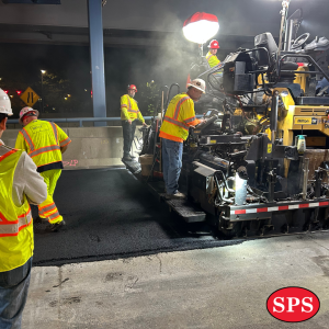 Men in safety vests watching paving happen. 